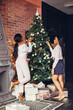 © prostooleh - Beautiful girls in a decorated room. Women near Christmas tree. Black ladies with gifts