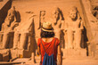 A young tourist in a red dress and straw hat walking towards the Abu Simbel Temple in southern Egypt in Nubia next to Lake Nasser. Temple of Pharaoh Ramses II, travel lifestyle