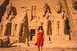 © unai - A young tourist in a red dress leaving the Abu Simbel Temple in southern Egypt in Nubia next to Lake Nasser. Temple of Pharaoh Ramses II