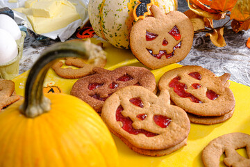 woman making cookies for halloween celebration at home with ginger dough and strawberry jam