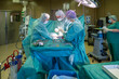 © karegg - team of gynecologists performs a caesarean section in an operating room