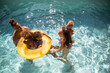 © Tom Merton/Caia Image - Happy family playing in inflatable ring in sunny summer swimming pool