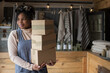 © Martin Barraud/Caia Image - Portrait confident female shop owner with stack of cardboard boxes