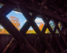 Looking Though The Lattice Wooden Architecture Of Covered Bridge At Fall Foliage  

