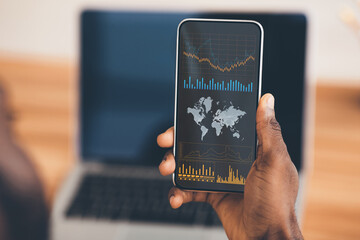 Poster - Mobile Trading. Black Businessman Holding Smartphone With Stock Market Data On Screen