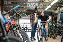 Male Bike Shop Owner Helping Customer With Mountain Bike