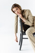 © LIGHTFIELD STUDIOS - trendy model in beige suit posing on wooden chair on white