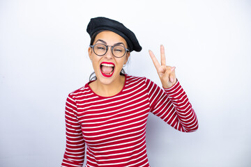 Young beautiful brunette woman wearing french beret and glasses over white background showing and pointing up with fingers number two while smiling confident and happy