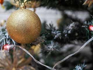 Decorations on a Christmas tree by a wall in a house. Winter season holidays theme.