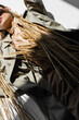 © LIGHTFIELD STUDIOS - cropped view of young woman in trench coat and scarf lying near wheat on white