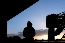 A Hooded Man Silhouetted Underneath A Road Bridge.