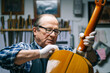 © Daniel González/Westend61 - Senior men polishing guitar while standing at workshop