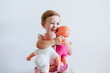 © Eva Blanco/Westend61 - Baby girl embracing toys while sitting against wall