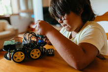 Boy Repairing Remote Controlled Car While Sitting By Table At Home