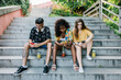 © Xavier Lorenzo/Westend61 - Young friends text messaging on smart phone while sitting on steps in park