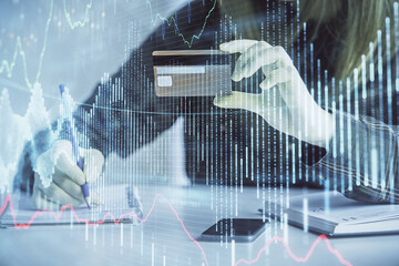 Double exposure of woman on-line shopping holding a credit card and financial graph drawing. Stock market E-commerce concept.