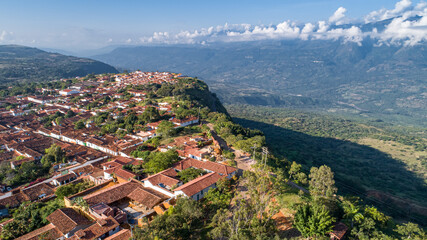 Wall Mural - Aerial view panorama of historic town Barichara, Colombia with white cloud covered mountain ridge in background