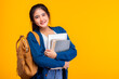© Nutlegal - Happy asian female college student smiling at camera on yellow background and copy space, holding laptop and books, hanging bagpack. Youth girl student is exchange student. education concept