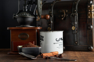 Vintage coffee grinder, coffer and coffee cup over wood in a dark enviroment