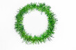 Round circle of bright green tinsel on a white background. Christmas decorations. New year concept