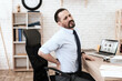 © freeograph - A man grabbed a sore back while sitting.