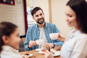 Wall Mural - Young Happy Family Eating Cakes in Cafeteria.