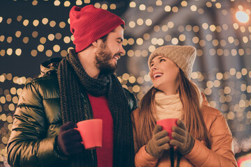 Poster - Photo of loving couple hold hot coffee beverage mug under x-mas evening illumination wear season tradition coats