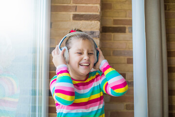 Close up portrait of young girl in headphnes. Happy, cheerful young girl at home