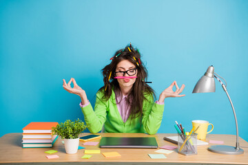 Poster - Portrait of peaceful girl sit table meditate have messy pencil hairstyle isolated over blue color background