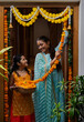 © IndiaPix - A MOTHER AND DAUGHTER LOOKING AT EACH OTHER HAPPILY WHILE DECORATING ENTRANCE WITH FLOWERS