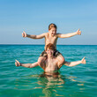 © travelview - brothers are enjoying the clear warm water at the beautiful beach and playing pickaback