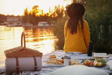 Wall Mural - Young woman spending time on pier at picnic, back view