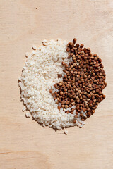 two piles of buckwheat and rice on a wooden background