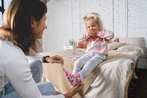 Cuadros en Lienzo Mom takes off her little daughter's socks and tickles her feet a little