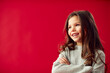 © Monkey Business - Portrait Of Young Girl With Folded Arms Against Red Studio Background Smiling At Camera