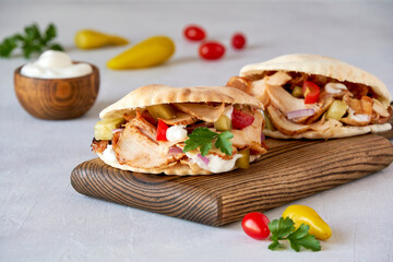 Shawarma with chicken  and garlic sauce in pita bread on wooden board. Closeup