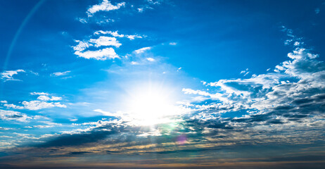 Wall Mural - Dramatic blue sky with sun and multicolor clouds at sunset or sunrise and circular lens flare