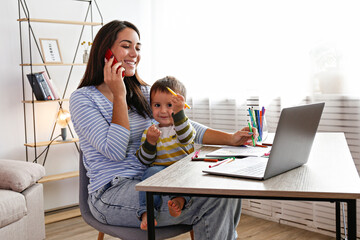 Young beautiful woman multitasking, working from home & teaching two year old son to draw. Woman spending quality time with her toddler child. Homeschooling concept. Close up, copy space, background.