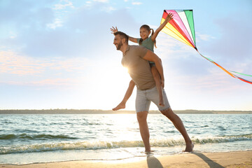 Canvas Print - Happy father and his child playing with kite on beach near sea. Spending time in nature