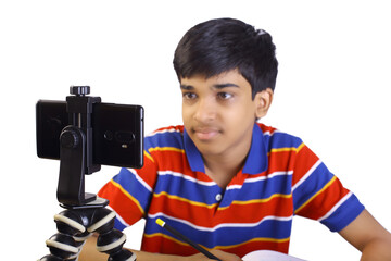 Wall Mural - Portrait of cute Indian boy using mobile phone while studying at home, remote education concept,