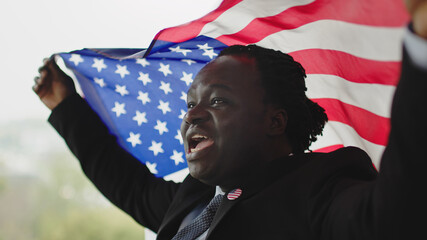 Portrait, young african american black man in formalwear with usa badge on the chest holding usa flag. High quality photo