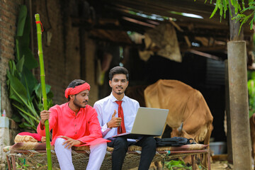 Wall Mural - Young indian agronomist showing some information to farmer in laptop at home