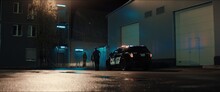 WIDE Police Officer Exiting A Car And Approaching Two Multi-ethnic Males Suspects Near Industrial Buildings At Night. Shot With Anamorphic Lens