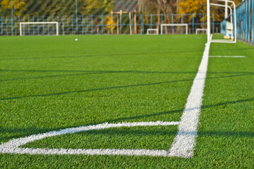 Soccer field texture close up. Grass in the stadium. Finely mown lawn for sports grounds. Straight lines are drawn in white paint. Restrictive zones at the stadium.