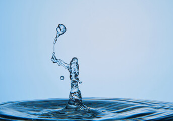 Water drop falling down. Abstract blue background.