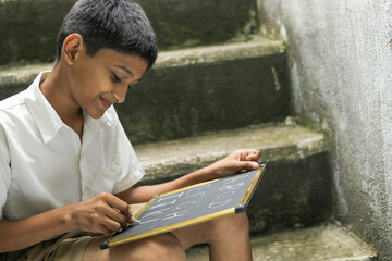 Indian child writing A B C D alphabet on Chalkboard