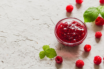 homemade raspberry jam on a concrete background with fresh raspberries, selective focus