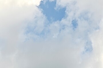 Light blue sky with light gray and white clouds in diffused light