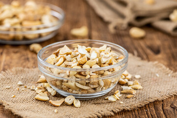 Wall Mural - Wooden table with chopped Cashew nuts (close-up shots, selective focus)