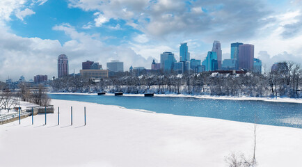 Downtown Minneapolis Winter View From Boom Island Park and Mississippi River with cloudy blue sky background